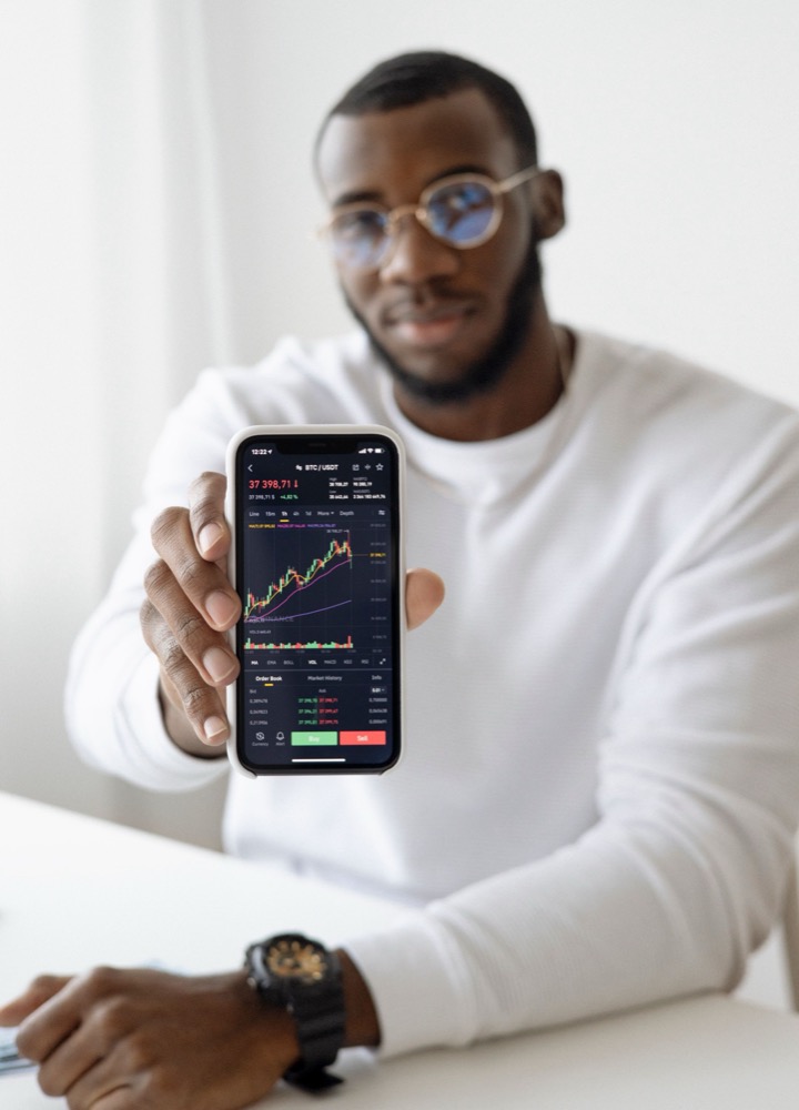 A man holding a phone with a trading application open